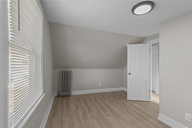 bonus room featuring light wood-type flooring, radiator heating unit, and vaulted ceiling