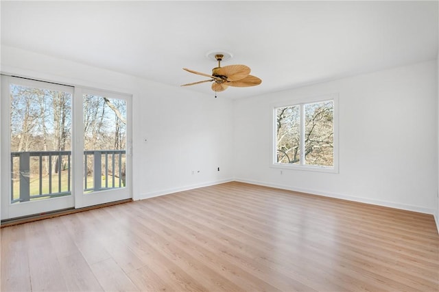 empty room featuring ceiling fan, plenty of natural light, and light wood-type flooring