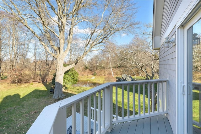 wooden terrace with a water view and a yard