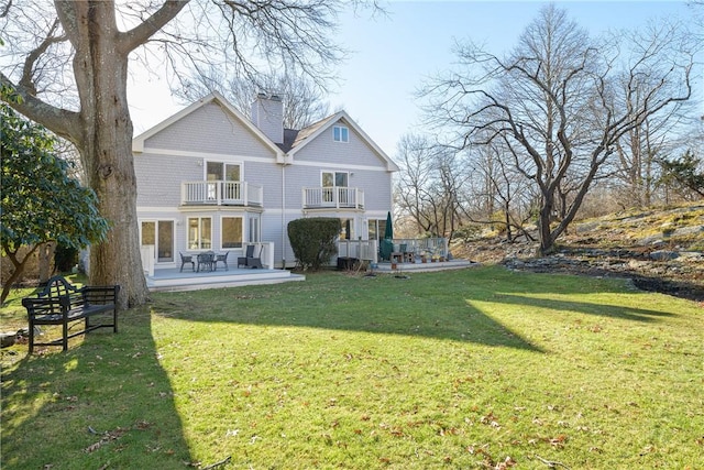 rear view of house with a balcony, a yard, and a patio area