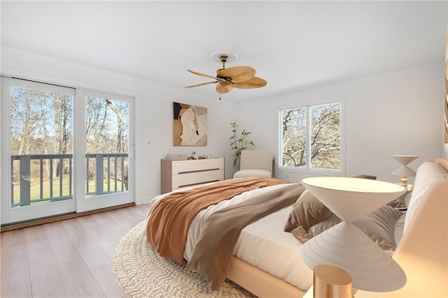 bedroom featuring ceiling fan, access to exterior, multiple windows, and light hardwood / wood-style flooring