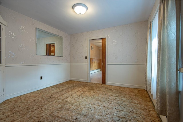 carpeted empty room featuring a baseboard heating unit