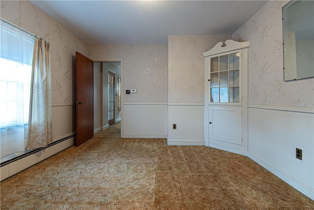 carpeted spare room featuring a baseboard heating unit