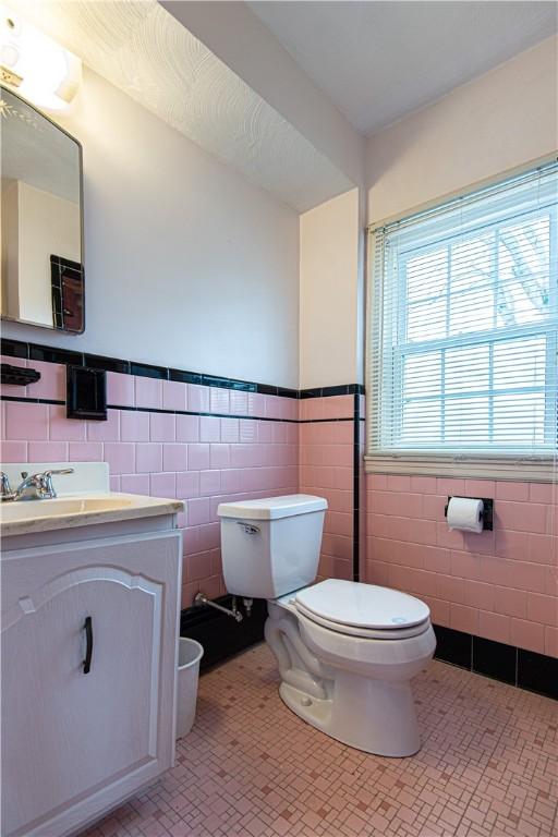 bathroom featuring vanity, tile walls, tile patterned floors, and toilet