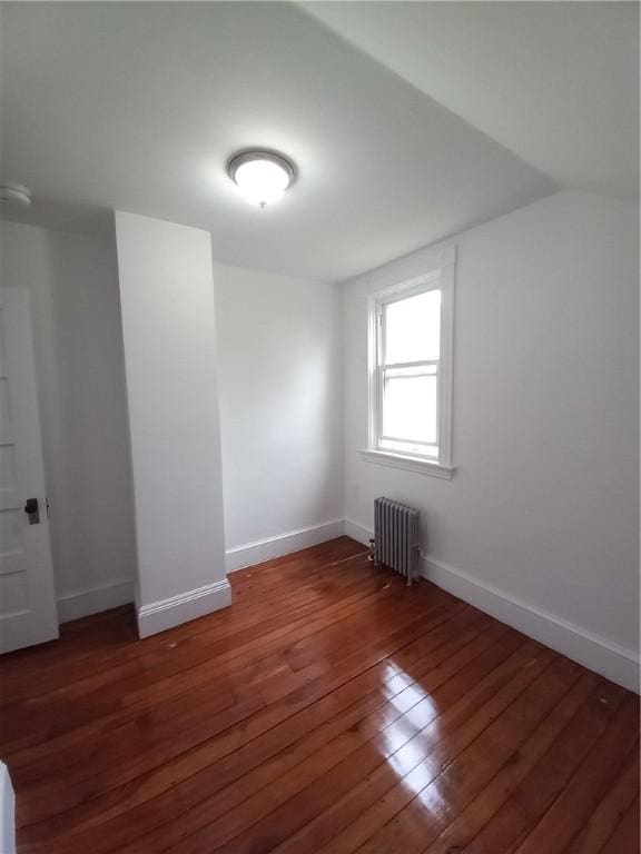 interior space with vaulted ceiling, radiator, and dark hardwood / wood-style flooring