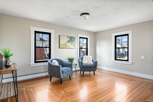 sitting room featuring light parquet flooring, plenty of natural light, and a baseboard heating unit