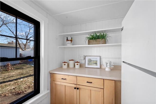 bar featuring light brown cabinets and white refrigerator