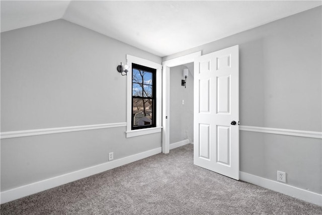 empty room featuring vaulted ceiling and carpet