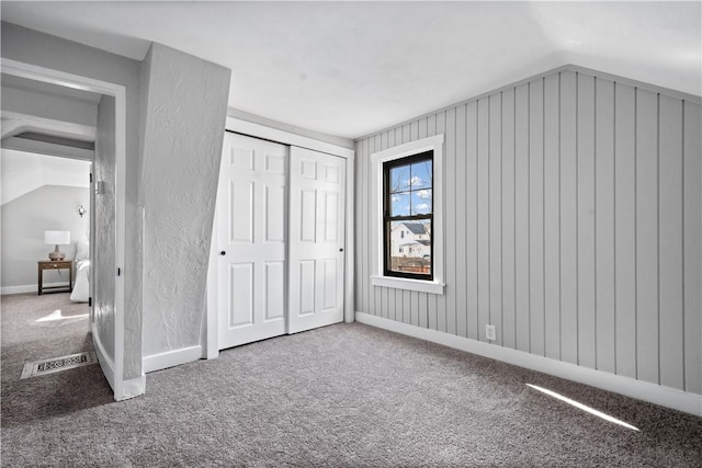 unfurnished bedroom with a closet, lofted ceiling, and carpet