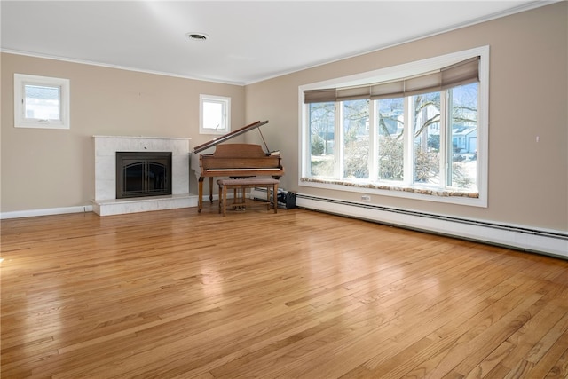 living room featuring crown molding, a baseboard radiator, a tile fireplace, and light wood-type flooring