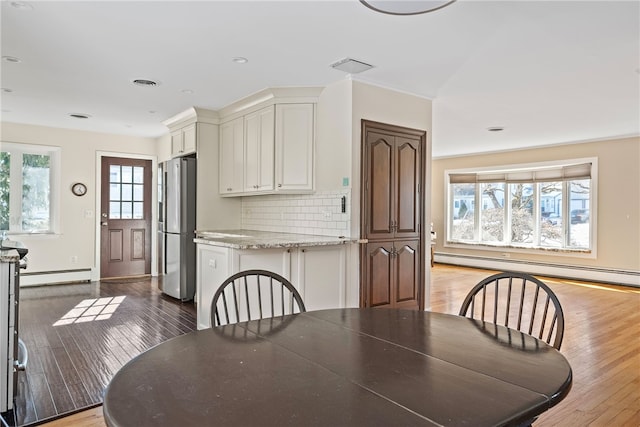 dining space with hardwood / wood-style flooring and a baseboard radiator