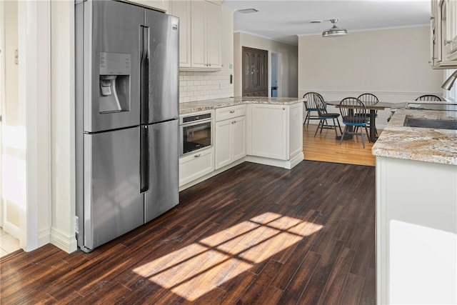 kitchen with appliances with stainless steel finishes, white cabinetry, sink, kitchen peninsula, and light stone countertops