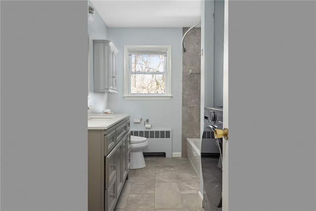 full bathroom featuring tiled shower / bath, radiator, vanity, toilet, and washing machine and dryer