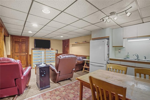 interior space featuring white fridge, sink, a paneled ceiling, and white cabinets