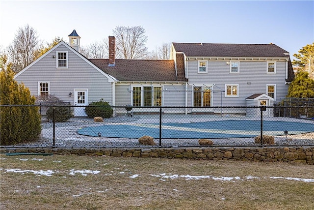 rear view of house featuring a covered pool and tennis court