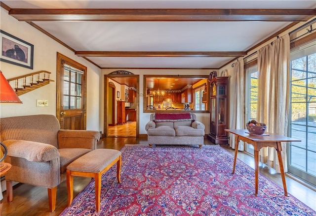 living room featuring wood-type flooring, ornamental molding, and beam ceiling