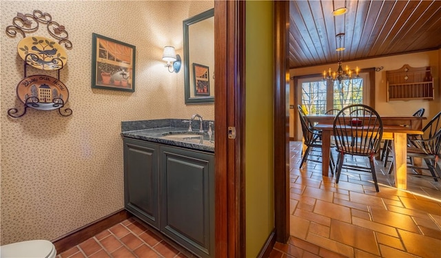 bathroom featuring an inviting chandelier, vanity, wood ceiling, and toilet