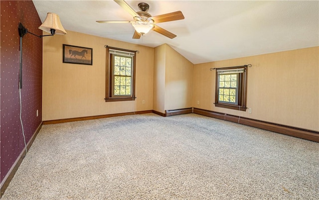 spare room featuring vaulted ceiling, a healthy amount of sunlight, baseboard heating, and carpet flooring