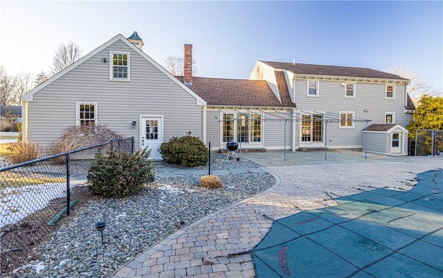 back of property featuring a patio area and a covered pool