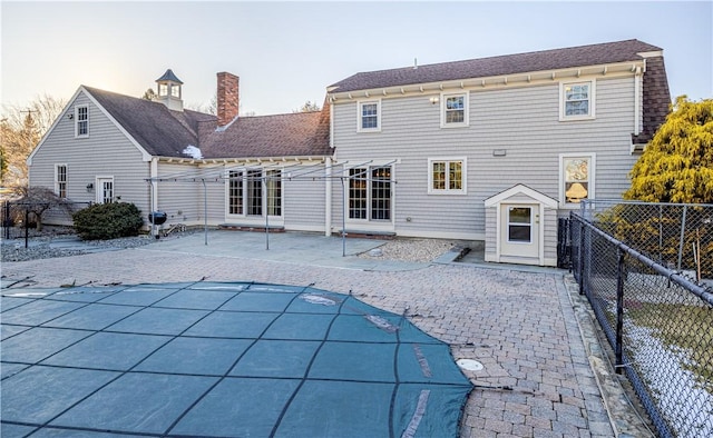 back house at dusk with a covered pool and a patio area