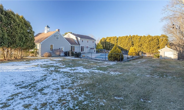 snow covered rear of property featuring a storage shed