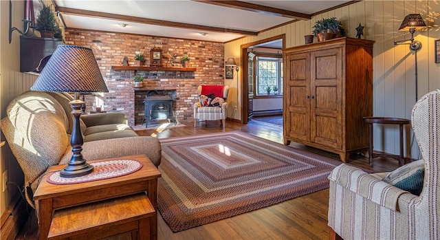 living room featuring beamed ceiling, a wood stove, and hardwood / wood-style flooring