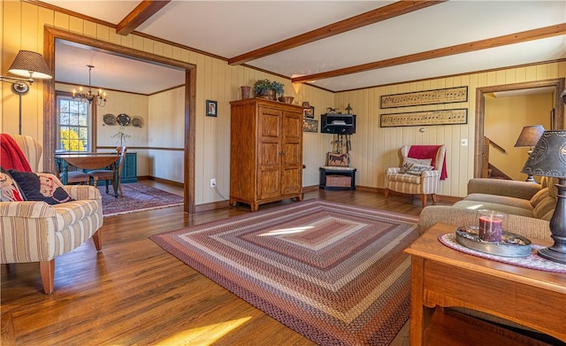 living room with beamed ceiling, ornamental molding, an inviting chandelier, and hardwood / wood-style floors