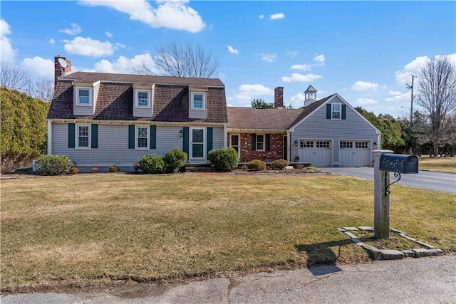 dutch colonial featuring driveway, a front lawn, and a chimney