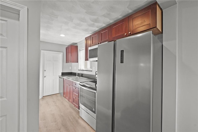 kitchen featuring appliances with stainless steel finishes, sink, and light hardwood / wood-style floors