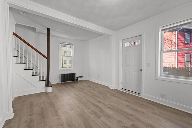 entryway with hardwood / wood-style flooring, crown molding, and radiator