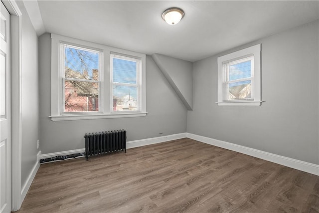 bonus room with wood-type flooring and radiator heating unit