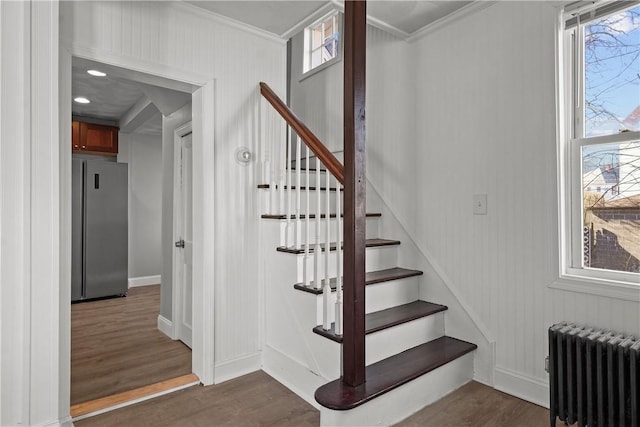 stairs with hardwood / wood-style flooring, radiator heating unit, and ornamental molding