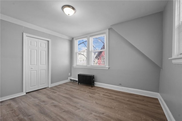 bonus room with radiator heating unit and light wood-type flooring