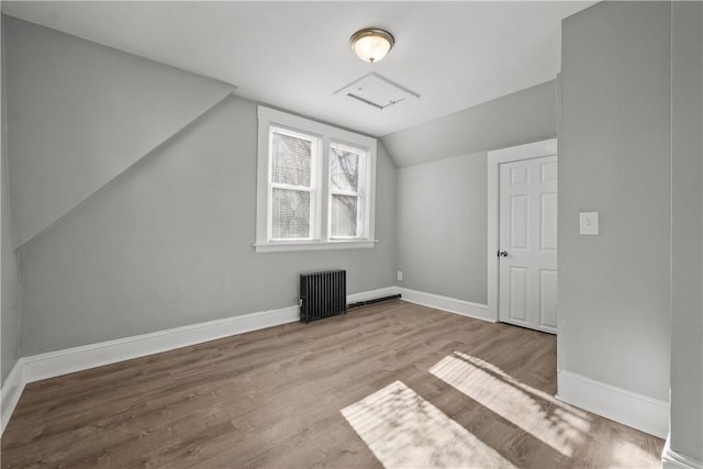 bonus room featuring vaulted ceiling, radiator heating unit, and light hardwood / wood-style floors