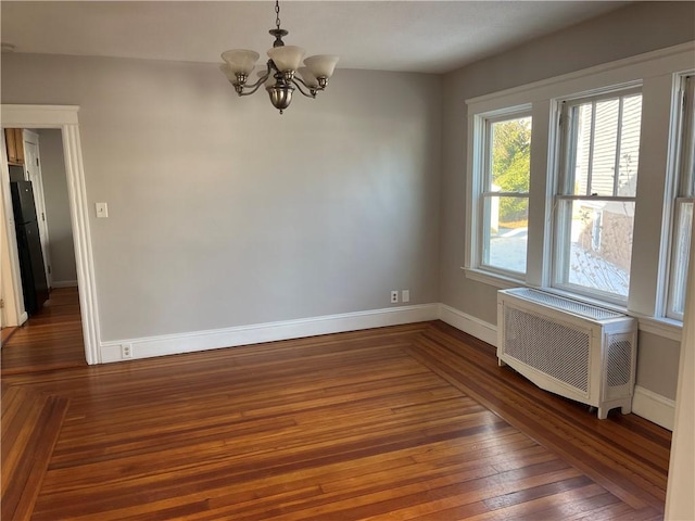 unfurnished room with dark hardwood / wood-style floors, radiator heating unit, and a chandelier