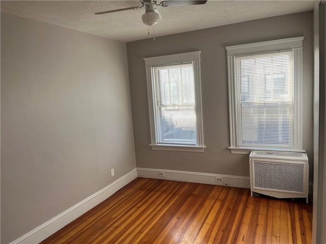 spare room with ceiling fan, wood-type flooring, a wall mounted AC, and a textured ceiling