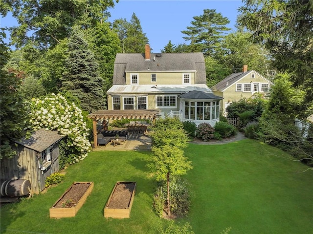 rear view of house featuring a pergola, a lawn, and a sunroom