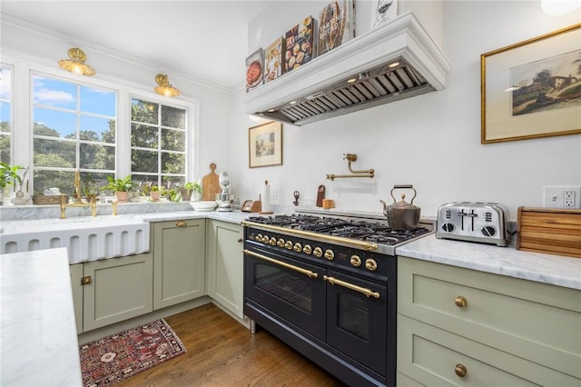 kitchen with green cabinets, premium range hood, double oven range, light stone counters, and dark hardwood / wood-style flooring