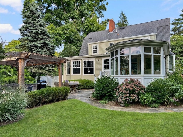 back of house with a sunroom, a lawn, and a pergola