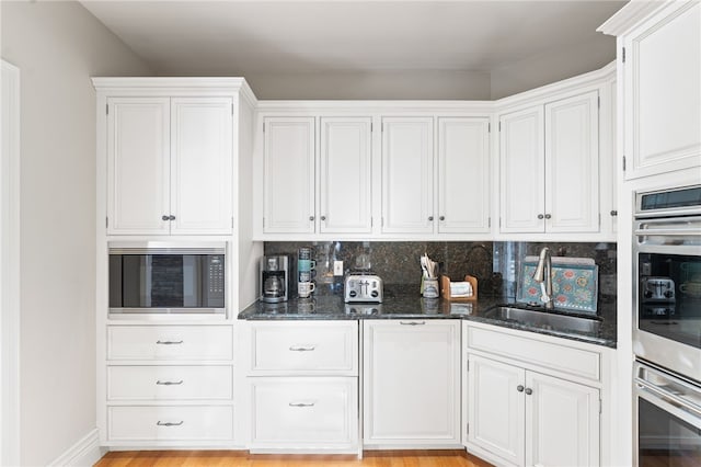 kitchen with built in microwave, sink, and white cabinets