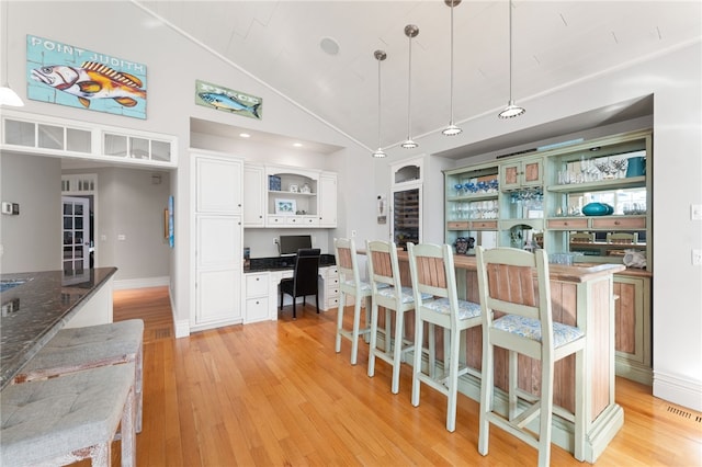 kitchen featuring pendant lighting, built in desk, white cabinets, and a kitchen bar