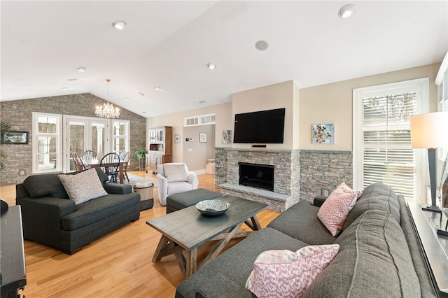 living room with light wood-type flooring, a fireplace, vaulted ceiling, and a wealth of natural light