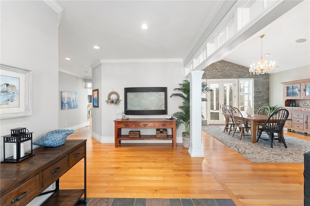 living room with ornate columns, crown molding, a chandelier, vaulted ceiling, and hardwood / wood-style floors