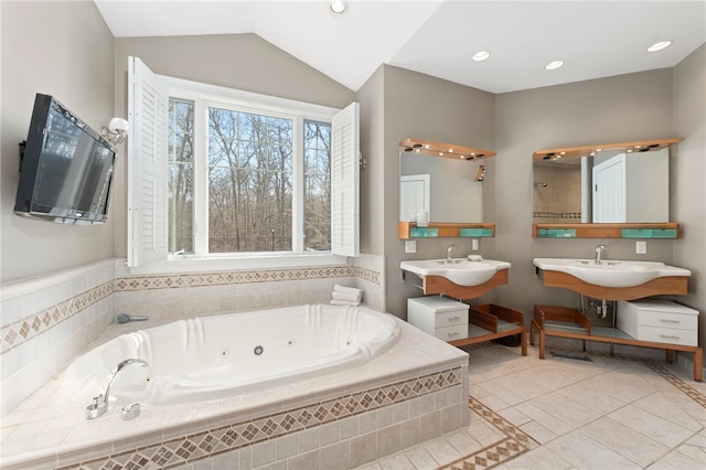 bathroom with lofted ceiling, tiled tub, tile patterned flooring, and double sink