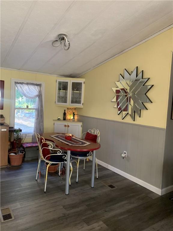 dining space with vaulted ceiling and dark wood-type flooring