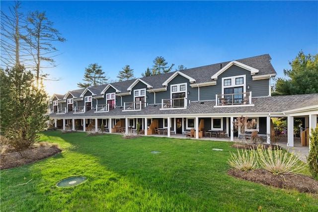 view of front of home with a balcony, a patio area, and a front lawn