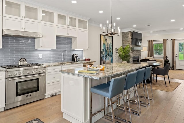 kitchen with stainless steel stove, light stone countertops, a center island, and white cabinets