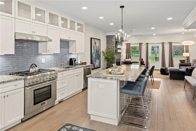 kitchen with appliances with stainless steel finishes, decorative light fixtures, light stone countertops, and sink