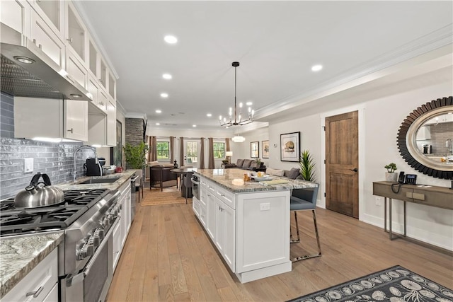 kitchen featuring white cabinetry, high end stainless steel range oven, ornamental molding, and a kitchen island