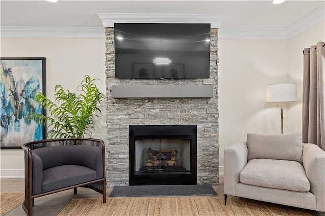 sitting room with hardwood / wood-style floors, crown molding, and a stone fireplace